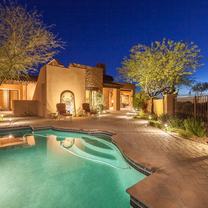 Luxury home backyard pool area in the evening.